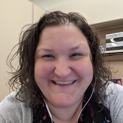 young Caucasian woman with shoulder length curly hair, smiling