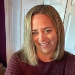 Medium length straight light brown hair, smiling face.