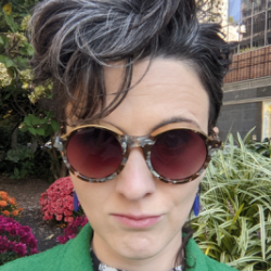 picture of Kathleen DiGiulio, a white woman with dark hair, wearing sunglasses and a green coat